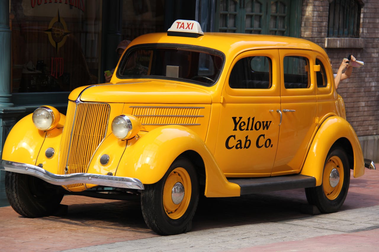 Classic yellow taxi cab parked in a city street with retro style.