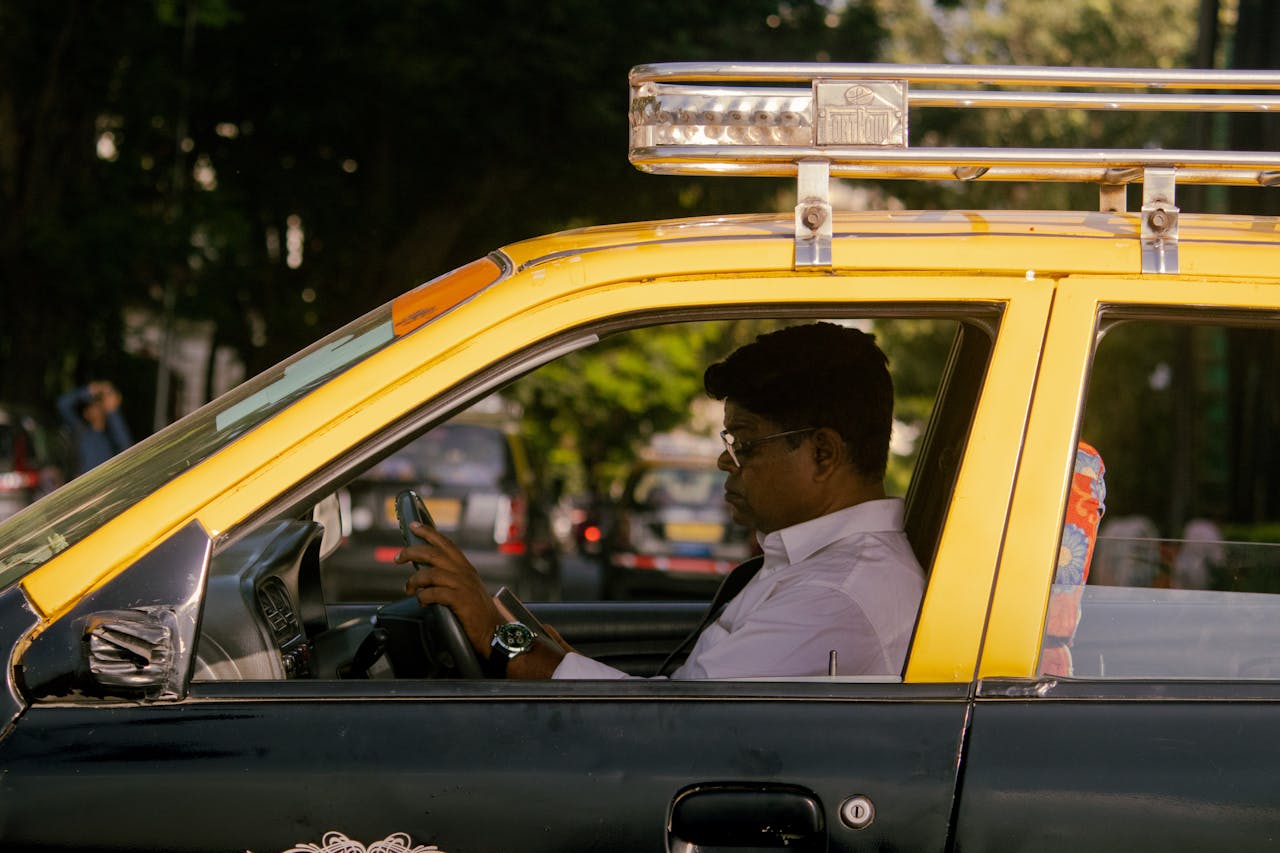 services-03 A taxi driver sits attentively in traffic in Mumbai, India, capturing urban life.