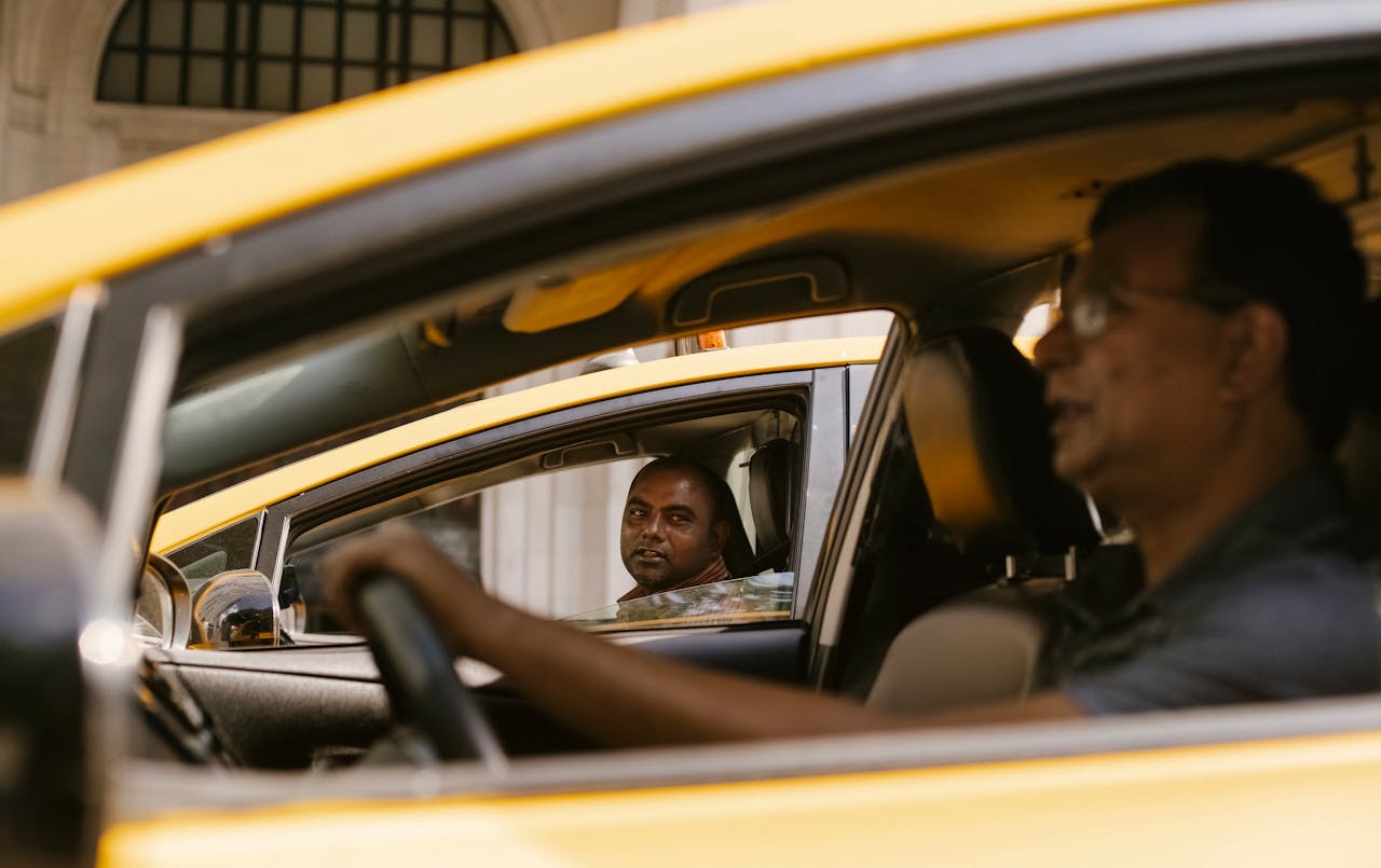 about-02 Side view of multiracial male friends talking while driving taxi cars in town in daylight